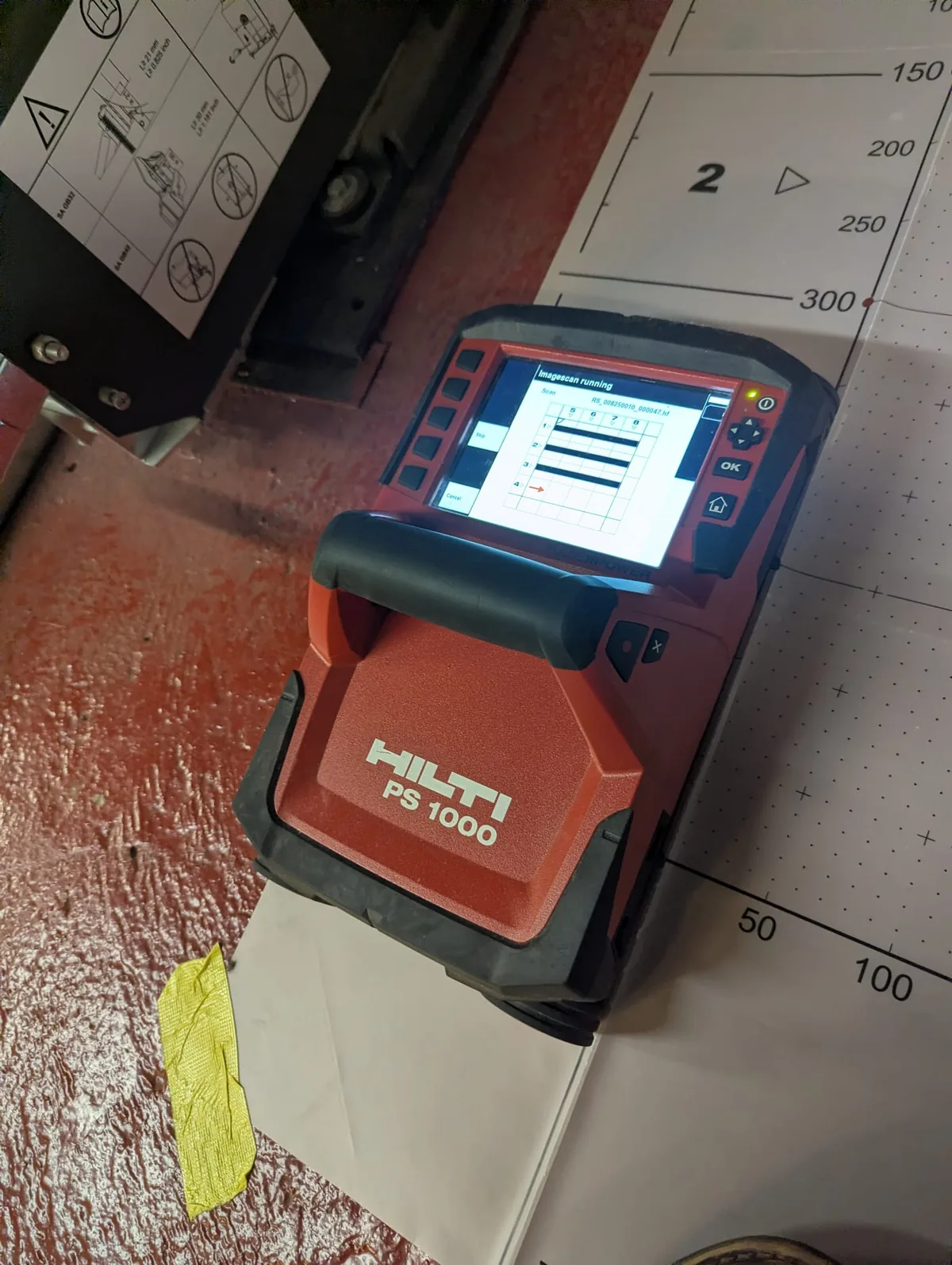 Hilti PS1000 GPR unit on a gridded scan sheet on the machine-room floor